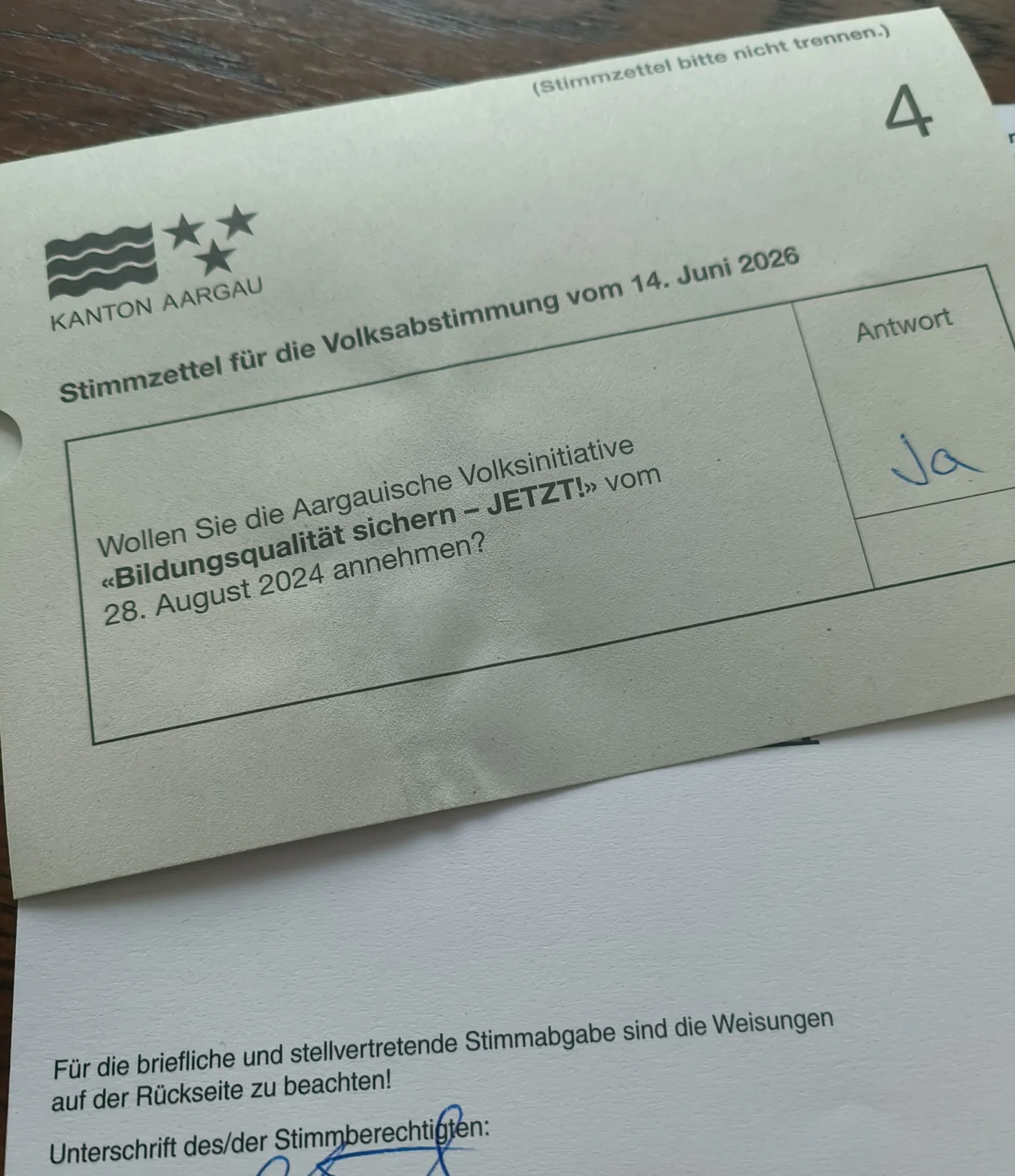 Das Bild zeigt einen Abstimmungszettel und einen Stimmrechtsausweis. Der Abstimmungszettel ist mit Ja beschriftet und der Stimmrechtsausweis unterschrieben.